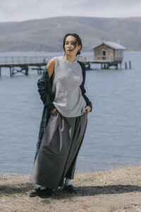 Grey sleeveless knit and wide grey skirt with a plaid overshirt carried at the shoulder