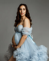Close-up of a pregnant woman in a soft blue tulle dress, highlighting her baby bump during a maternity photoshoot in Yucaipa by Kaitlyn Dawn Photography.