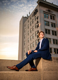 Senior portrait in downtown Mobile, Alabama— in his suit with the Van Antwerp building in the background.