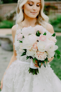 A close-up image of the bride holding her flower bouquet, focusing on the bouquet's intricate details and the bride's expression