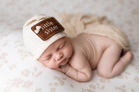 Baby girl posed with a Little Sister cap at Jennifer Brandes Photography in St. Clair, Minnesota.