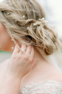 Detail photo of bride's ring as she combs her fingers through her hair