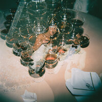 Film photograph of champagne glasses creating a dreamy double exposure wedding detail shot.