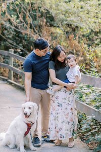 family of 3 smiling with their golden retriever