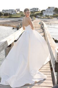 Bride looks over her shoulder while standing on boardwalk during sunset.