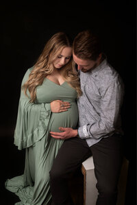 Pregnant woman in a sage green gown posing outdoors during a Cleveland maternity photography session