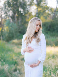 Blonde pregnant woman looking over her shoulder and holding her bump