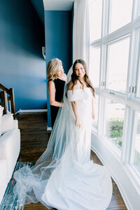 A heartwarming moment of a mother helping her daughter into her wedding dress, capturing the intimate and emotional pre-wedding preparations
