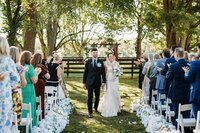 Newlyweds walking back down the aisle surrounded by guests at an outdoor ceremony at Bradshaw Duncan House, one of the best wedding venues in Kentucky.