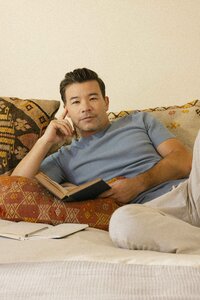 Man reading in bed with a journal beside him, mental health vertical
