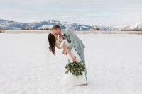Bride & groom in romantic embrace set against snowy open space at this Granby Ranch in Colorado.