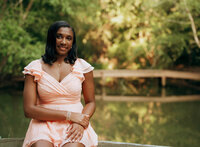 Senior portrait at Bella Sera Gardens in Loxley, Alabama — walking a gravel path near the pond
with greenery behind her.