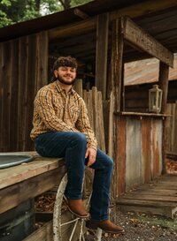 Senior portrait at Circle B Lake in Wilmer, Alabama — sitting on an old wagon wheel in brown
cowboy boots.
