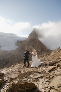 Couple walking a ridgeline on whaleback mountain at sunset with isolated peak in the background.