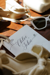 Photograph of wedding shoes, invitation and sunglasses