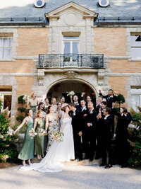 A joyful and refined group shot of a wedding party on the steps of Cairnwood Estate, capturing a real moment of celebration.