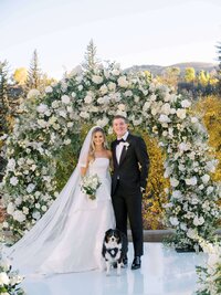 Bride and groom share a romantic kiss at the altar with their dog by their side at their black-tie wedding at Westin Riverfront in Vail, Colorado.