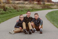 Three brothers sitting together on the grass during a Cleveland family photography session