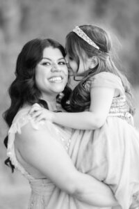 Black and white portrait of the Dilorio family mother holding her daughter as the daughter kisses her during a heartfelt outdoor photography session in Las Vegas.