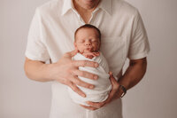 Newborn Photographer in Charleston -Father embraces his infant during Newborn Portrait Session in Charleston, SC.