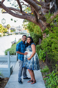 expecting couple holding each other during outdoor maternity portrait session in Venice Beach, California