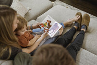 A family reads a book together on the couch in the living room
