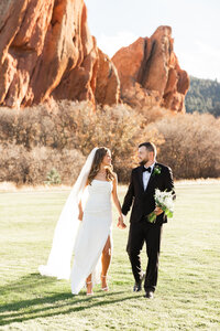 Arrowhead Golf Course wedding portraits—bride and groom walking with red rocks behind (Littleton, CO)
