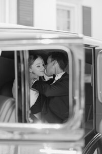 black and white image of bride and groom kissing in classic car in grosse pointe