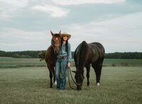 Senior portrait at Triple T Farms in Fruitdale, Alabama — posing with two horses in a field,
holding one’s head.