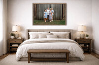 Framed family portrait displayed above a bed in a neutral bedroom showing wall art from a New Bern family photography session