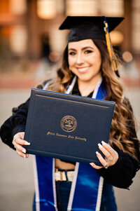 Senior girl holding up MTSU diploma