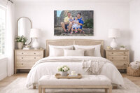 Family portrait canvas displayed above a neutral bedroom bed styled in soft coastal farmhouse tones in New Bern NC