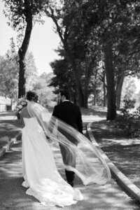 Bride and groom walking together outdoors with flowing veil captured in Detroit wedding photography