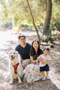 family of 3 smiling with their golden retriever