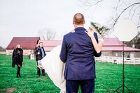 Behind the scene photo of groom holding bride, Ivory Door Studio team can be seen working in the background