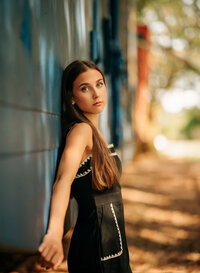Senior portrait in downtown Foley, Alabama — leaning against a stationary blue train car.