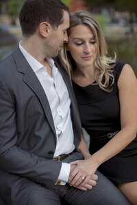 Central park engagement photos, Deborah Zoe Photography. A couple sit on the water's edge in Central Park.