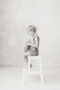A black and white photo of a little boy and his stuffed toy during his mothers maternity session taken in a Dallas/Fort Worth photography studio.