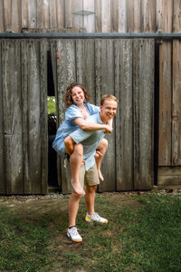 Teen brother giving his sister a piggyback ride during an outdoor family photography session in New Bern