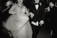 Bride and groom hold hands and running during their new years eve wedding exit as guests cheer around them.