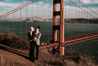 handsome and happy couple embracing at sunset on a cliff overlooking the city of san francisco at sunset near the golden gate bridge
