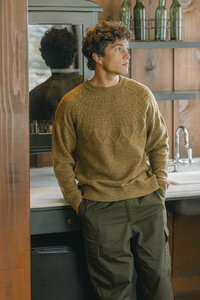 Olive sweater and olive utility trousers photographed in a boathouse interior