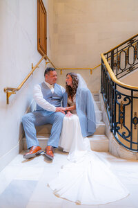 bride and groom sitting on stairs at san francisco city hall wedding