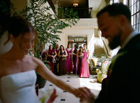 Bride and groom dancing as bridesmaids watch nearby.