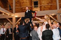 A winter Jewish wedding reception in Sturbridge, MA in the Berkshires with the couple in chairs dancing to the Hora.
