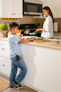 Mother and son cooking together at the kitchen counter