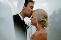 Groom kisses bride on forehead under wedding veil during intimate Chisholm Minnesota wedding portrait session.