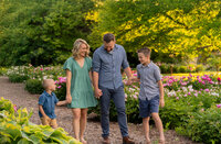A family of four walking hand in hand and smiling at one another during their family session in West Bend, Wisconsin