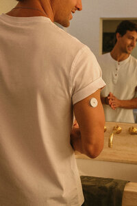 Man in the bathroom mirror with a wearable health monitor on his arm