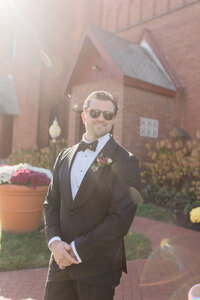 Groomsmen in sunglasses smiles before walking down the aisle